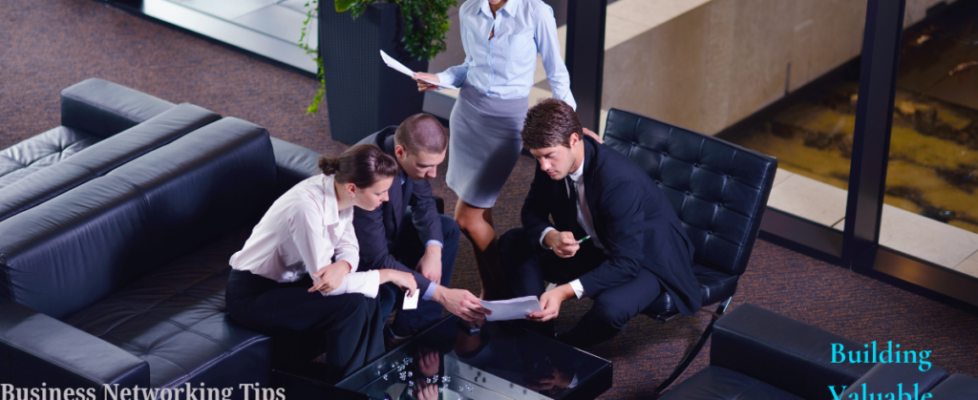 A group of four business professionals are gathered around a table in a modern office setting, discussing documents. The text "Business Networking Tips for Entrepreneurs" and "Building Valuable Connections" is visible in the image.